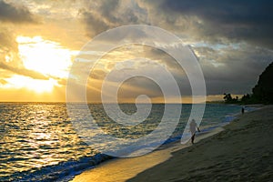 Awesome sunset beach walk after tropical storm, golden sun rays sunbeams opening dark cloudy sky