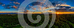 Awesome sunset over a forest at summertime, panoramic arial view with dramatic clouds.