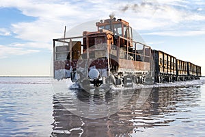 Awesome train rides on rail in the water with white salt on the background of beautiful blue sky