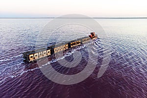 Awesome train rides on rail in the water with white salt on the background of beautiful blue sky. aerial view, view from