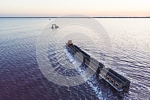 Awesome train rides on rail in the water with white salt on the background of beautiful blue sky. aerial view, view from