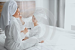 Awesome woman with daughter sit holding make-up brushes