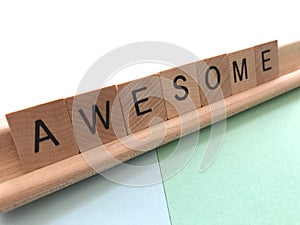 Awesome in wood alphabet letters on a simple coloured background