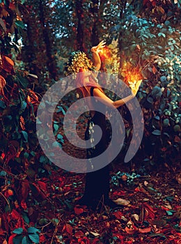 Awesome young witch conjures in the forest photo
