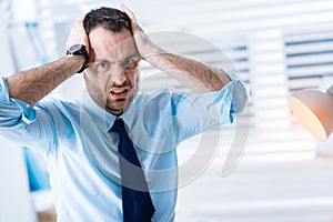 Unhappy bearded man holding his head and expressing his negative feelings