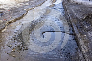 Awfully bad asphalt city road with a pit and puddle