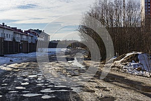 Awfully bad gravel road with pits in mud and puddles in spring in Russia