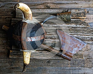 Ax horned helmet and viking signal horn on rough wooden table top view