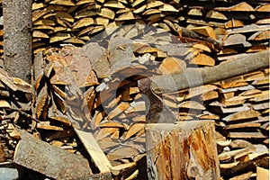 An ax impaled on a stump against the background of firewood in the sarp