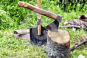 Ax and shovel in the forest. An axe stuck in a stump