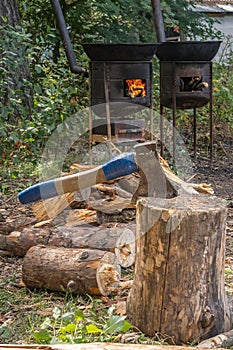 Ax stuck into a wooden block against the background of firewood and a stove with fire