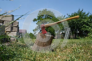 A ax in a stump and a scale in a garden in summer.