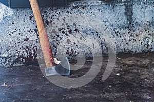 an axe with blood drops in front of a wall, cutting pigs at the slaughterhouse