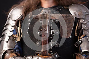 The axe of a medieval knight against the background of his torso in armor.