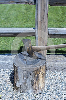 Axe is placed in an old chopping block made of a cut log.