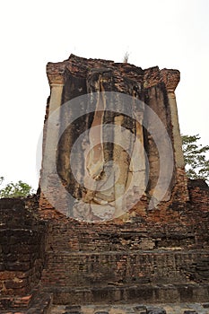 On axis view of badly eroded walking Buddha statue on east facing wall of mondop image hall, Sukhothai Historical Park, Thailand