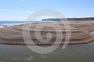 AXMOUTH, DEVON,ENGLAND - JULY 12TH 2020: A man and a woman stand on the shingle spit near Axmouth looking out to sea