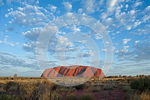 Ayers Rock, Uluru; glowing in morning sun, blue sky with small clouds