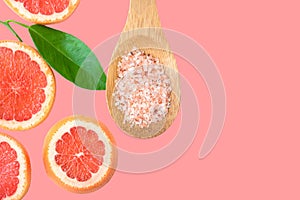 Ayurveda face skin scrub ingredients Himalayan salt in wooden spoon sliced grapefruit green leaf on cherry pink background