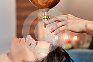 Ayurveda massage alternative healing therapy.beautiful caucasian female getting shirodhara treatment lying on a wooden table in