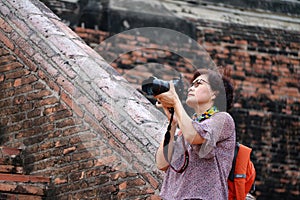 Women tourists taking pictures and background ancient brick at Yai Chaimongkol Temple, Thailand