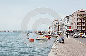 Sea banks past the Turkish town with moored fishing boats, and buses on town road