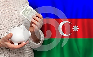 Azerbaijani woman with money bank on the background of Azerbaijan flag. Dotations, pension fund, poverty, wealth, retirement