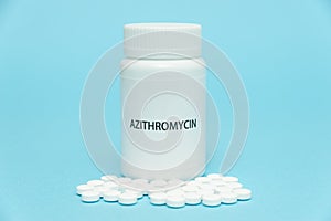 AZITROMYCIN antibiotic in white bottle packaging with scattered pills. Treatments for COVID-19. isolated on blue background