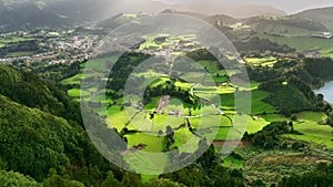 Azores nature on sunny day. Aerial shot of green meadows, mountains and Furnas city on Sao Miguel Island, Azores