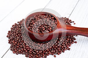 Azuki beans in wooden scoop on white table background