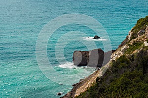 The azure sea against the backdrop of mountains and green trees