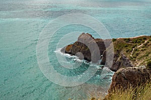 The azure sea against the backdrop of mountains and green trees