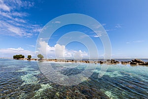 Azure turquoise blue lagoon, small uninhabited reef island motu full of dangerous rocks and mangroves trees. Pohnpei, Oceania.