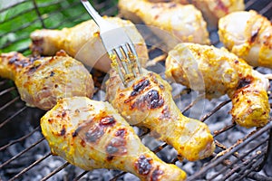 B-B-Q, tasty grilled chicken drumsticks fried outdoors at the stake close-up. juicy pieces with a crust turn over with a fork
