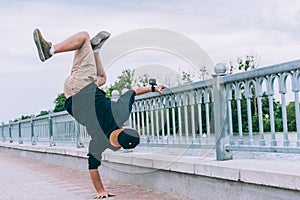 B-boy Break Dancer stands on one arm with an action camera