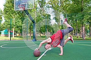 B-boy doing stunt trick on basketball field with ball