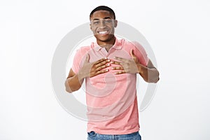 B-day boy grinning from happiness and joy being thankful and pleased with cool gifts pressing palms to breast smiling