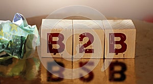 B2B on wooden cubes with crumpled 100 euro bill and reflection. Business to business sales marketing concept