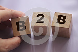 B2B abbreviation in letters on wooden cubes. Business to Busness concept Hand put a cube B to the row. Business marketing strategy