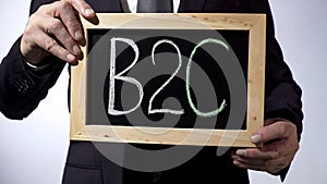 B2C, business-to-consumer written on blackboard, businessman holding sign