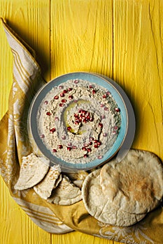 Baba ganoush or mutabal, Middle Eastern eggplant dip sauce garnished with pomegranate seeds with a rustic napkin and pita bread