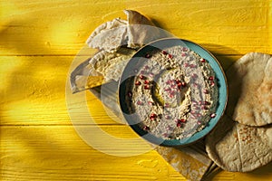 Baba ganoush or mutabal, Middle Eastern eggplant dip sauce garnished with pomegranate seeds with a rustic napkin and pita bread