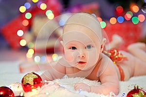 Babe with ared bow lies on a background of Christmas lights