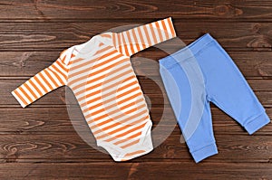 Babies bodysuits and pants on wooden background