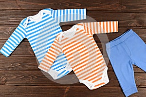 Babies bodysuits and pants on wooden background. Baby clothes photo