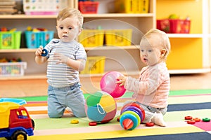 Babies boy and girl playing on floor with toys. Kids toddlers in creche or nursery