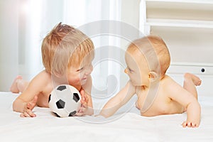 Babies boy and small girl play with football ball