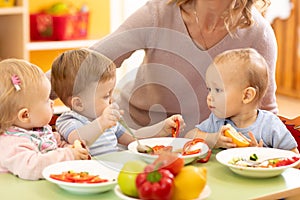 Babies eating healthy lunch in nursery