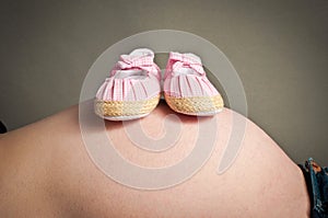 Babies first shoes resting on a pregnancy bump