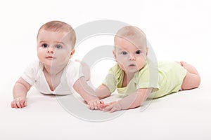 Babies girl and boy lying on a white background and holding hand